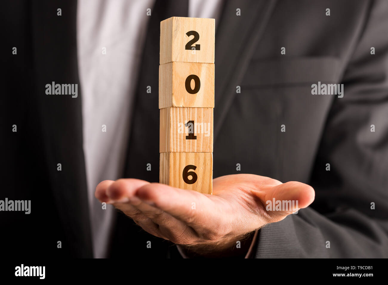 Male hand holding four stacked wooden cubes with 2016 sign. Stock Photo