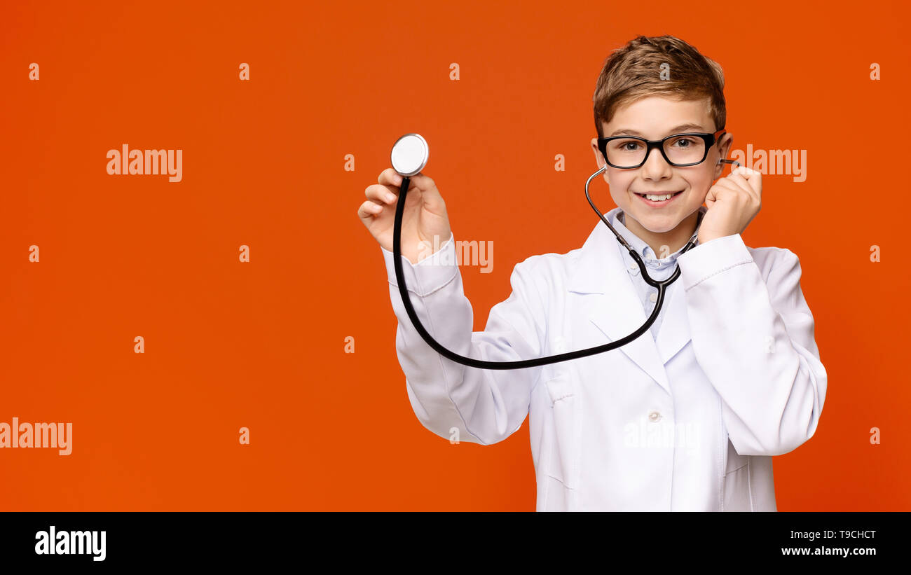Smiling little boy in medical uniform playing with stethoscope Stock Photo