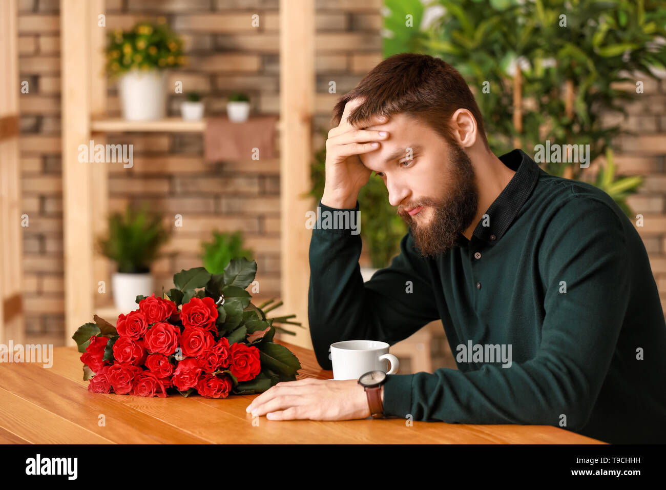 Upset man waiting for his girlfriend in cafe Stock Photo