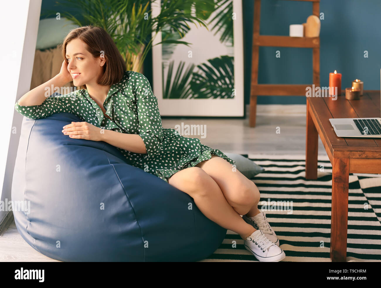 Young woman sitting on beanbag chair at home Stock Photo - Alamy