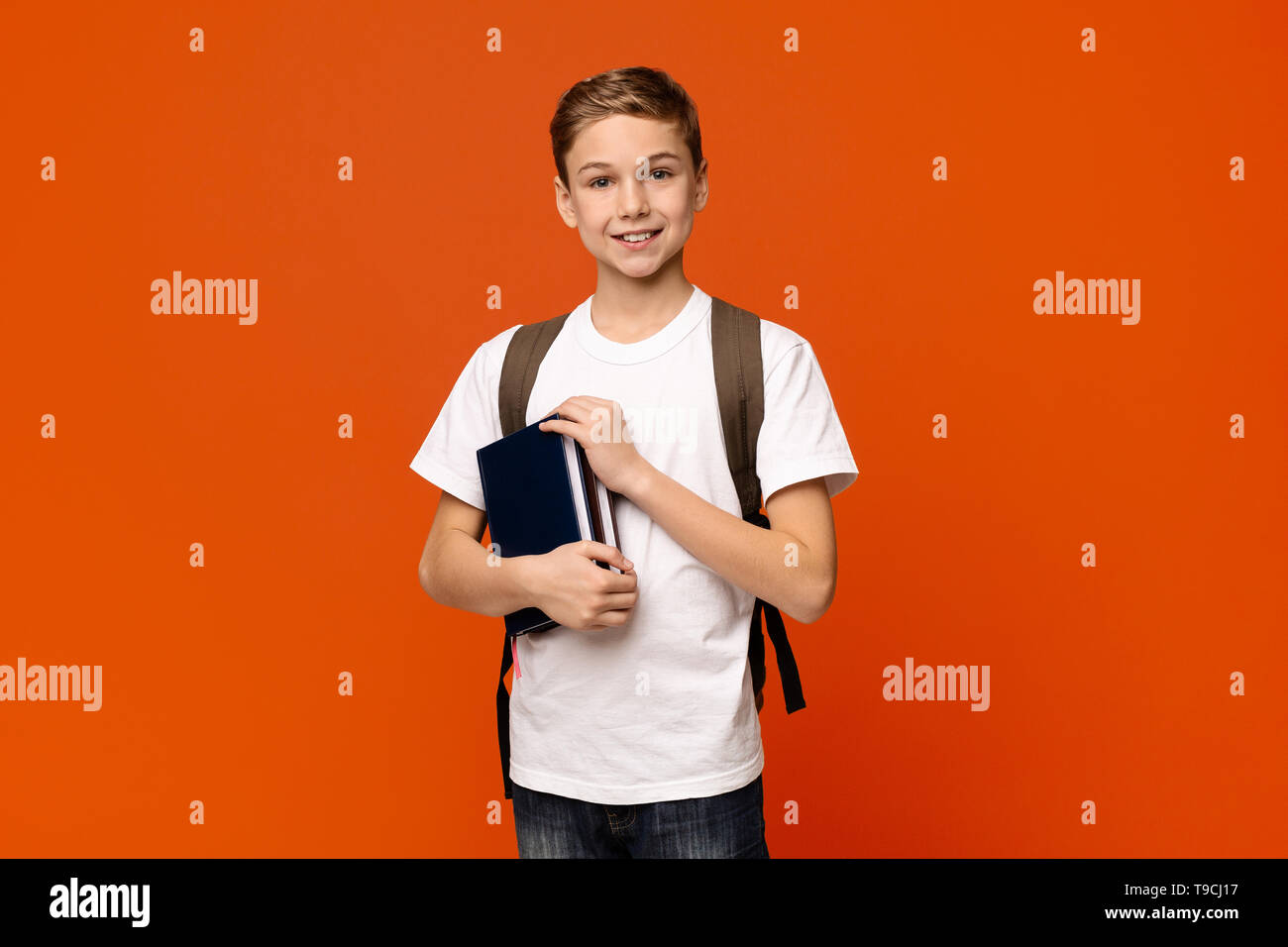 Cheerful boy with backpack holding books Stock Photo