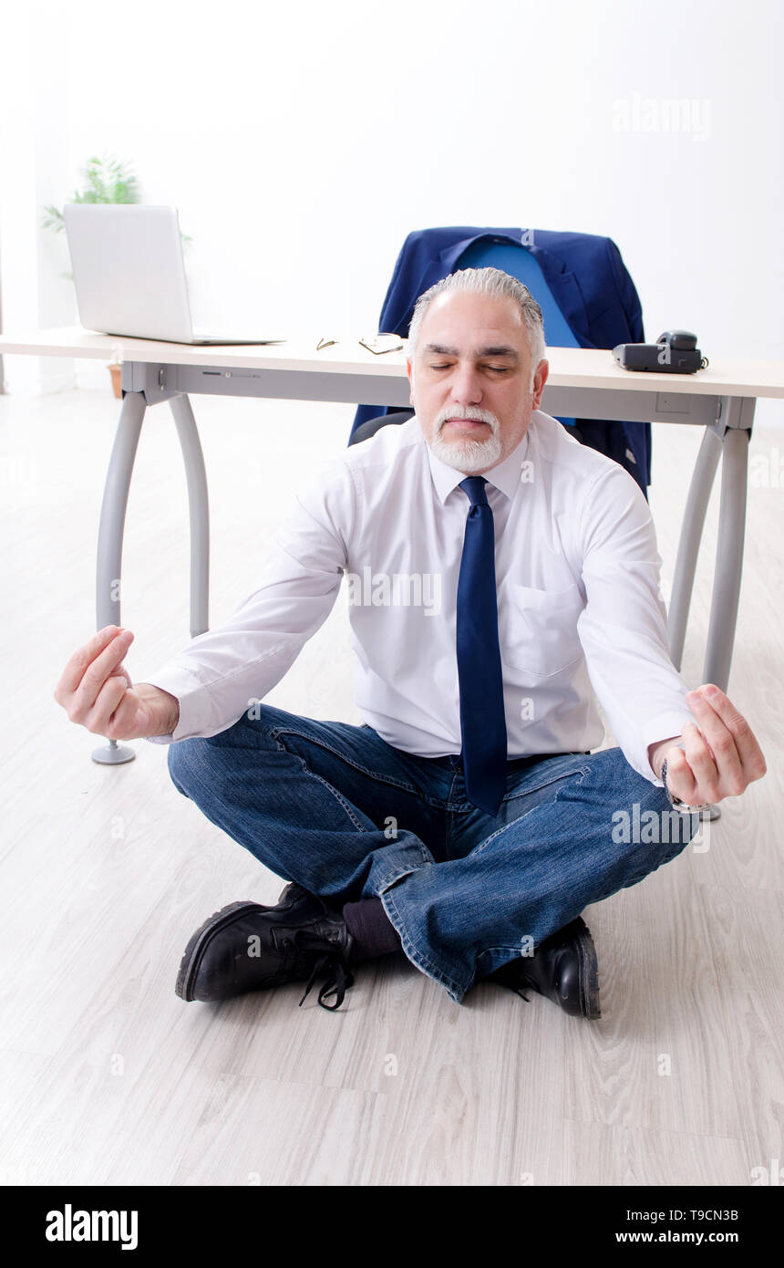 Aged businessman doing yoga exercises in the office Stock Photo - Alamy