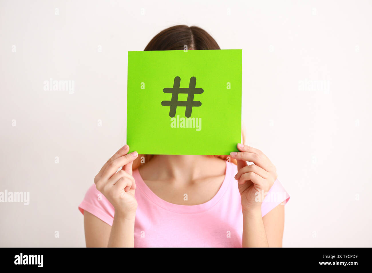 Woman holding sheet of paper with hashtag sign on white background ...