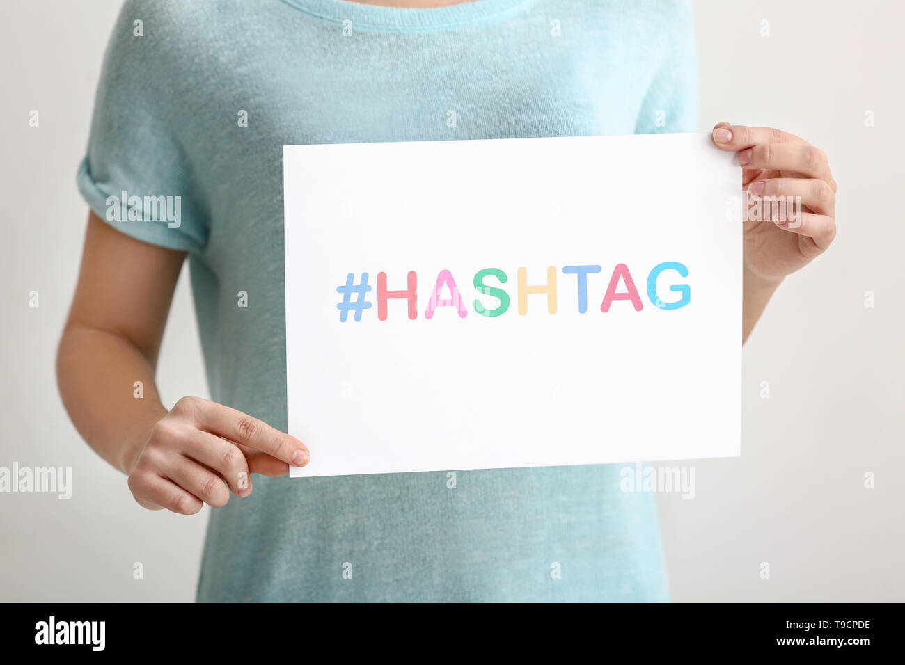 Woman holding sheet of paper with hashtag on light background Stock ...