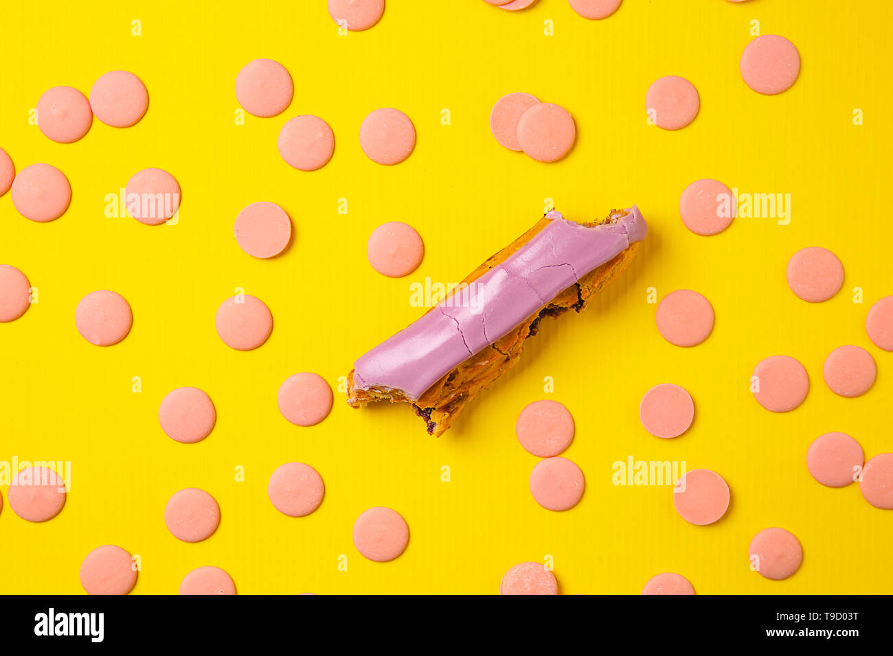 Bitten eclair with chocolate chips on color background Stock Photo