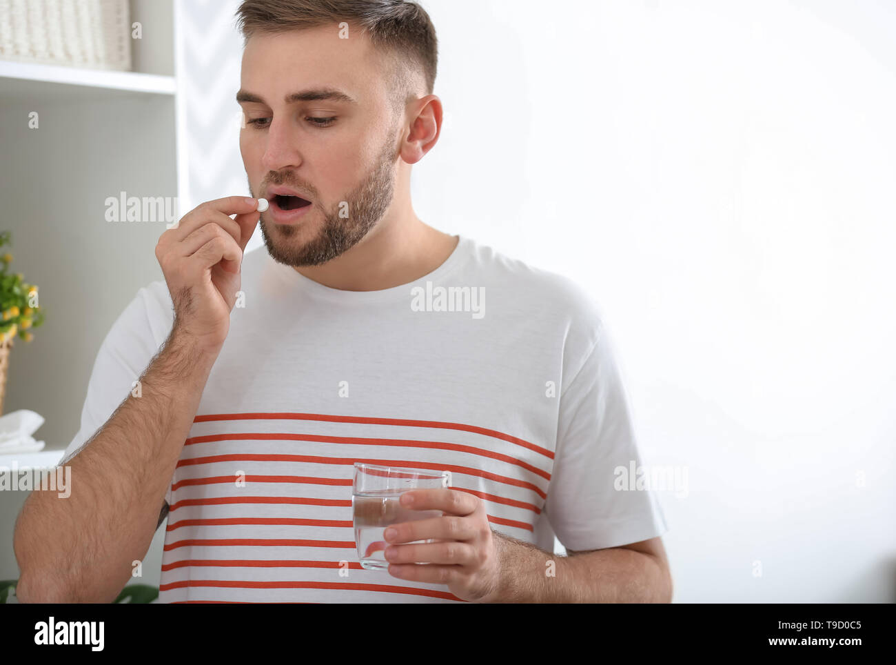 Young man ill with flu taking medicine at home Stock Photo