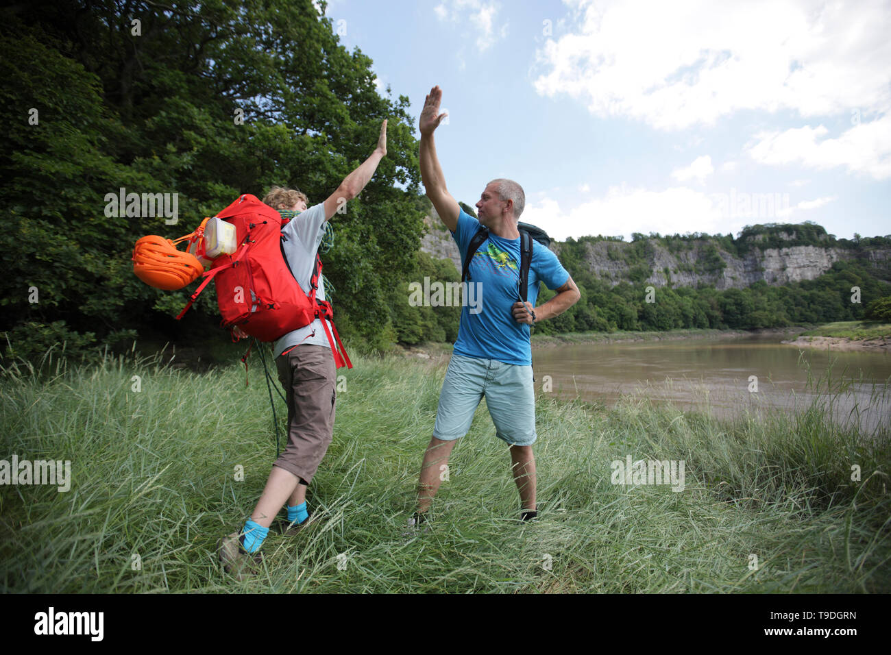 Two male climbers high five to celebrate their successful climb at Lancaut cliffs on the England/Wales border. Stock Photo