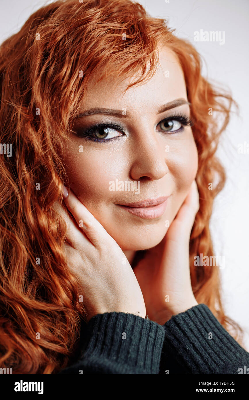 Charming, pretty, cute, lovely redhead woman touching cheeks with both palms, enjoying her perfect face skin after cream, mask, lotion, peeling. Head  Stock Photo