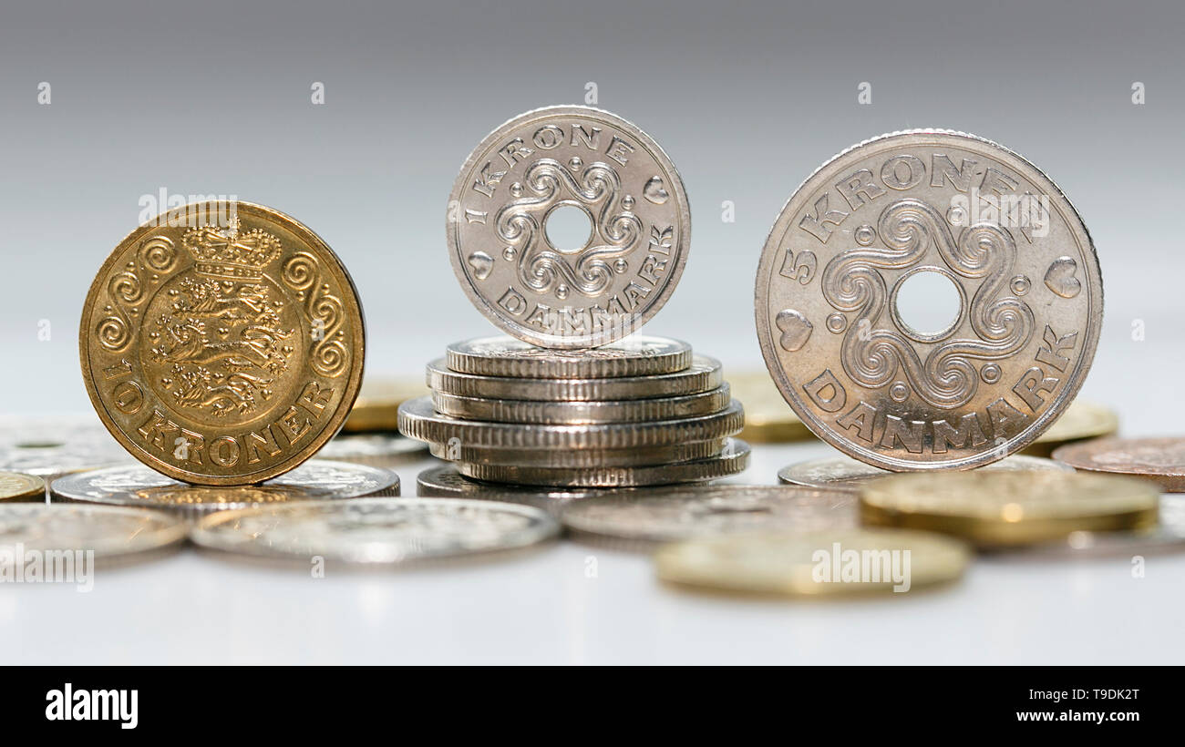 Mixed Kroner coins standing on a stack of Danish coins with selective focus. The krone is the official currency of Denmark, Greenland. Stock Photo