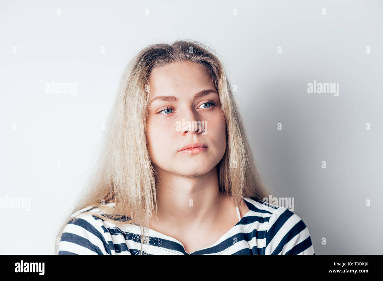 young beautiful sad woman serious and concerned looking aside and thoughtful facial expression, feeling depressed on white background. Negative emotio Stock Photo