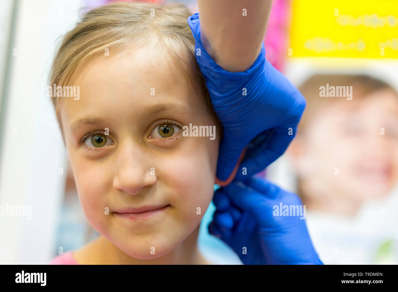 Girl pierced ear in the beauty salon. Adorable little girl having ear
