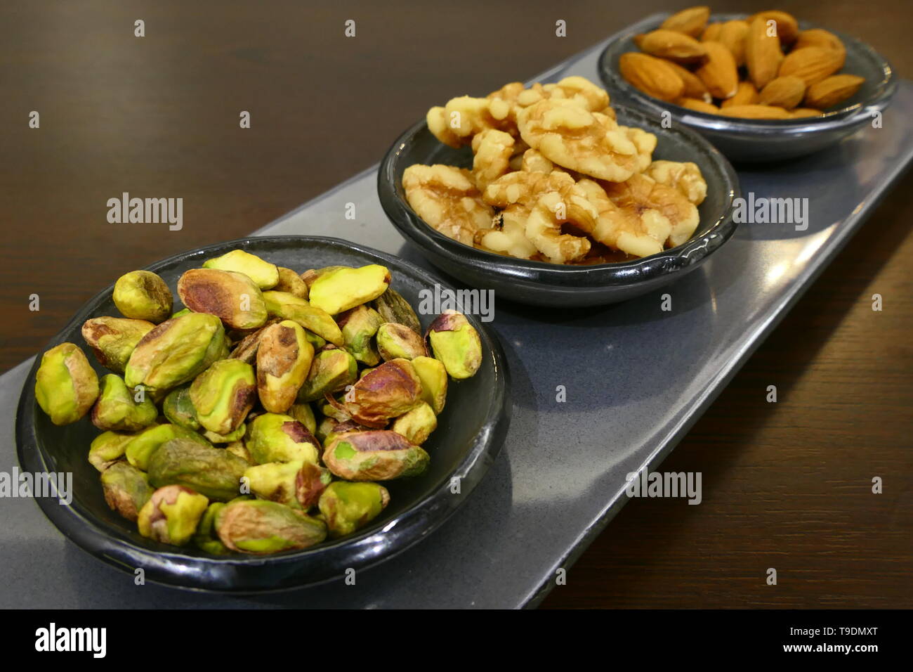 Bowls with three different nut varieties, including: walnuts, pistachios and almonds Stock Photo