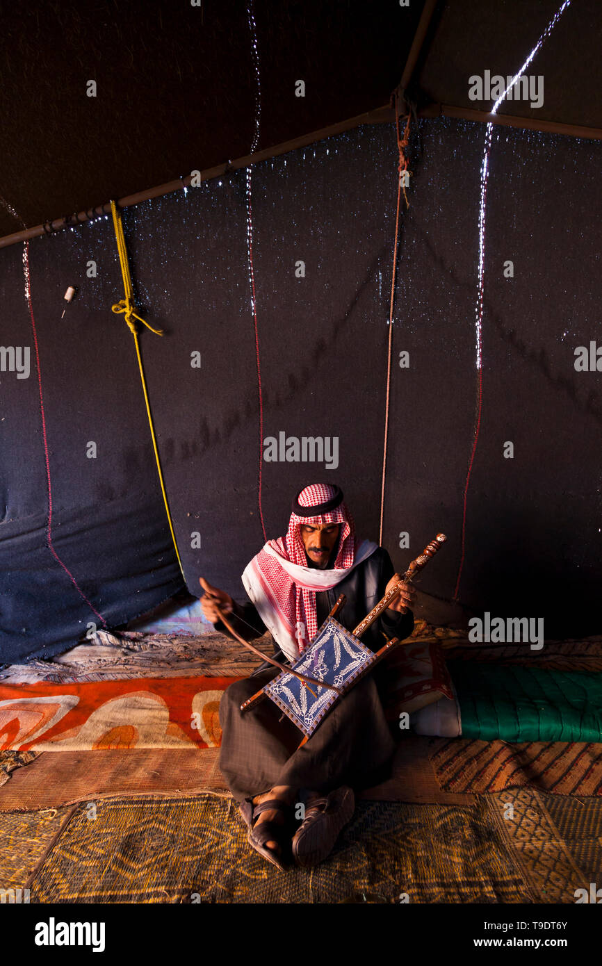 Beduino en la jaima tocando el instrumento musical Al Rababah, Wadi Rum, Jordania, Oriente Medio Stock Photo