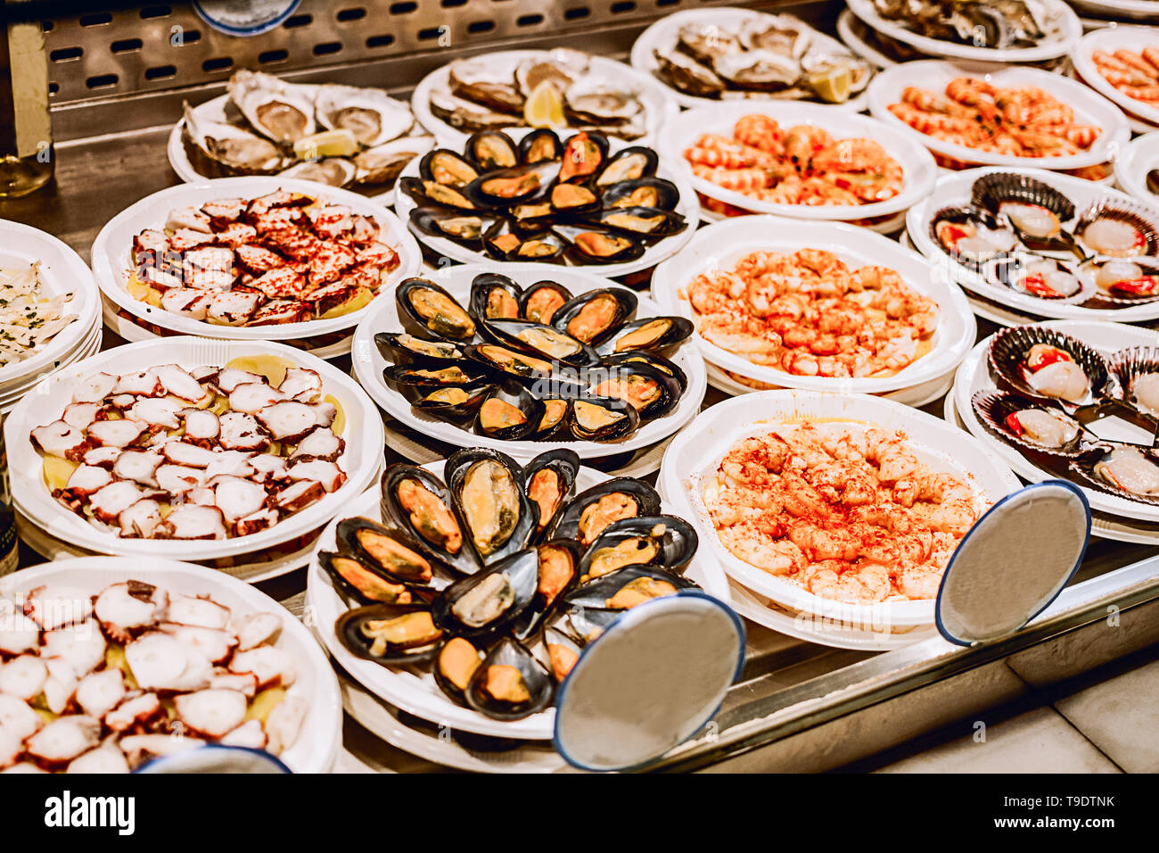 Seafood selection at the buffet counter. sea mussels in a disposable plate surrounded with fish and prawns on the counter. Stock Photo