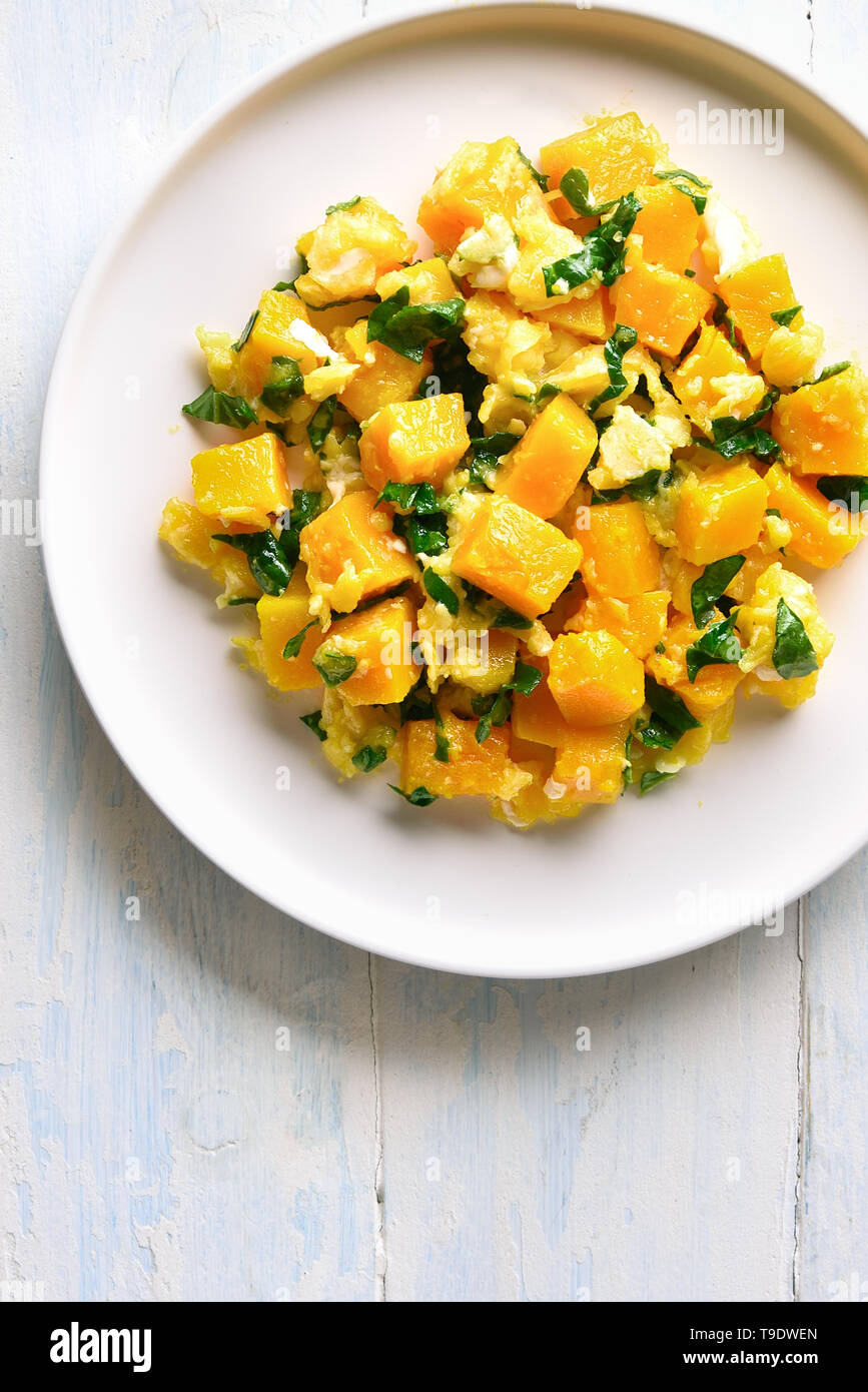 Pumpkin and egg stir fry in thai style. Stir-fried pumpkin with eggs on plate over white wooden background with copy space. Top view, flat lay Stock Photo