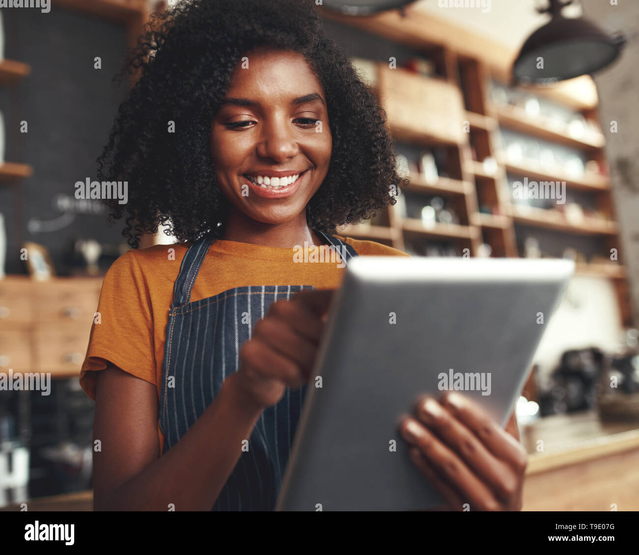 Smiling female cafe owner using digital tablet Stock Photo