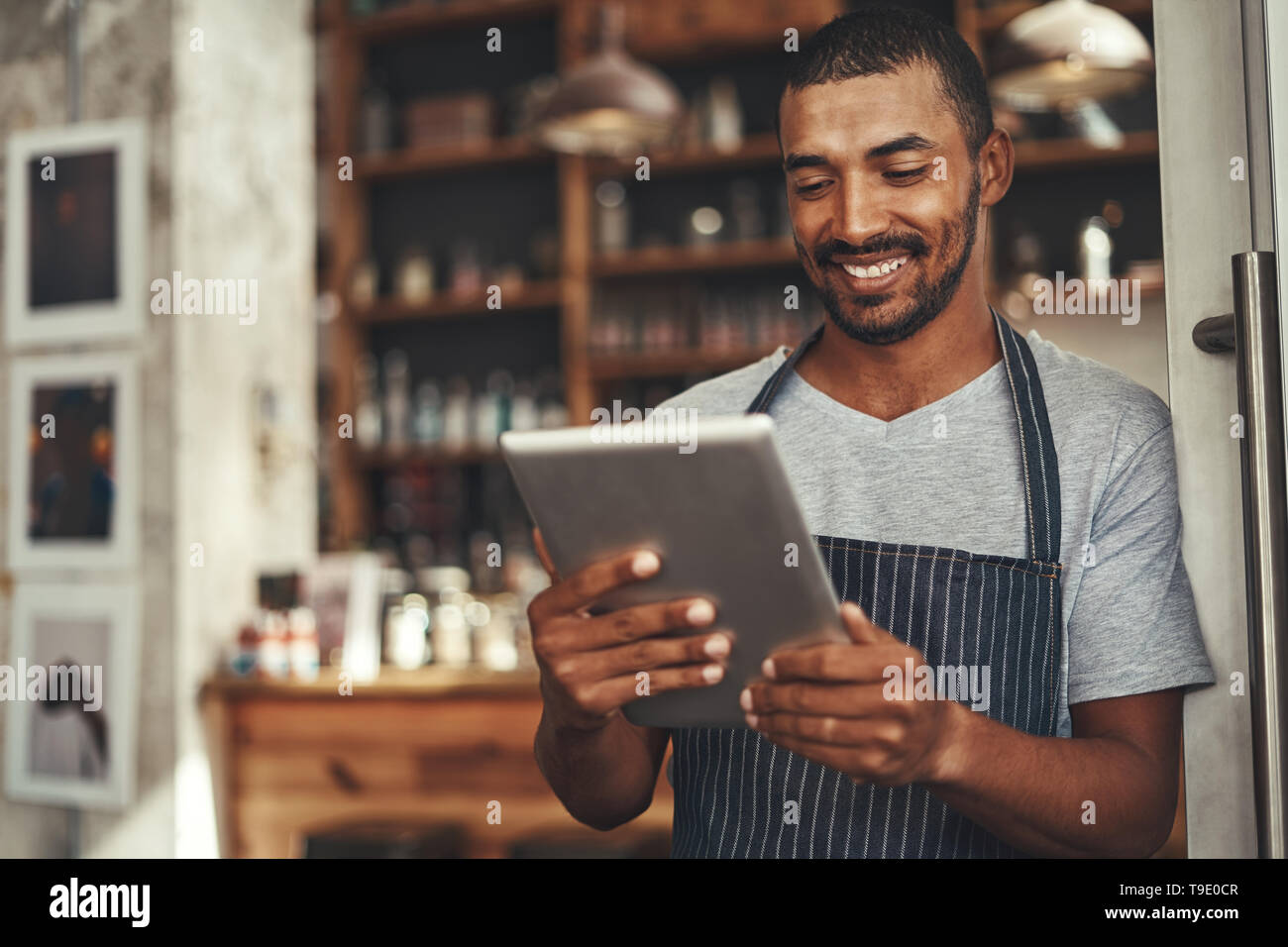Successful barista cafe owner looking at digital tablet Stock Photo