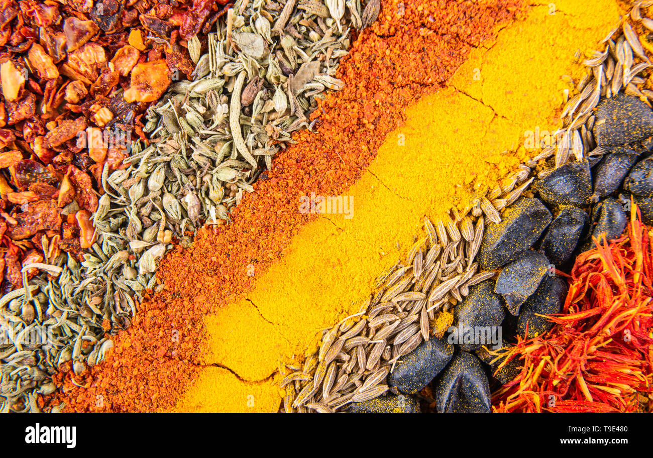 Colorful set of different spices for eastern dish pilaf. Diagonal spicy stripes includes satureja, curcuma, cuminum, barberry, paprika and tagetes. Vi Stock Photo