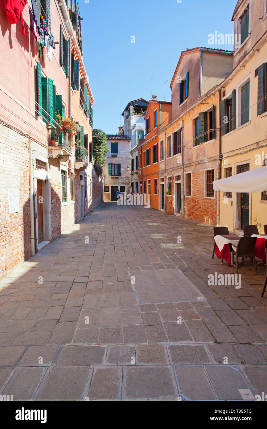 Venetian alley way and empty outdoor restaurant Stock Photo