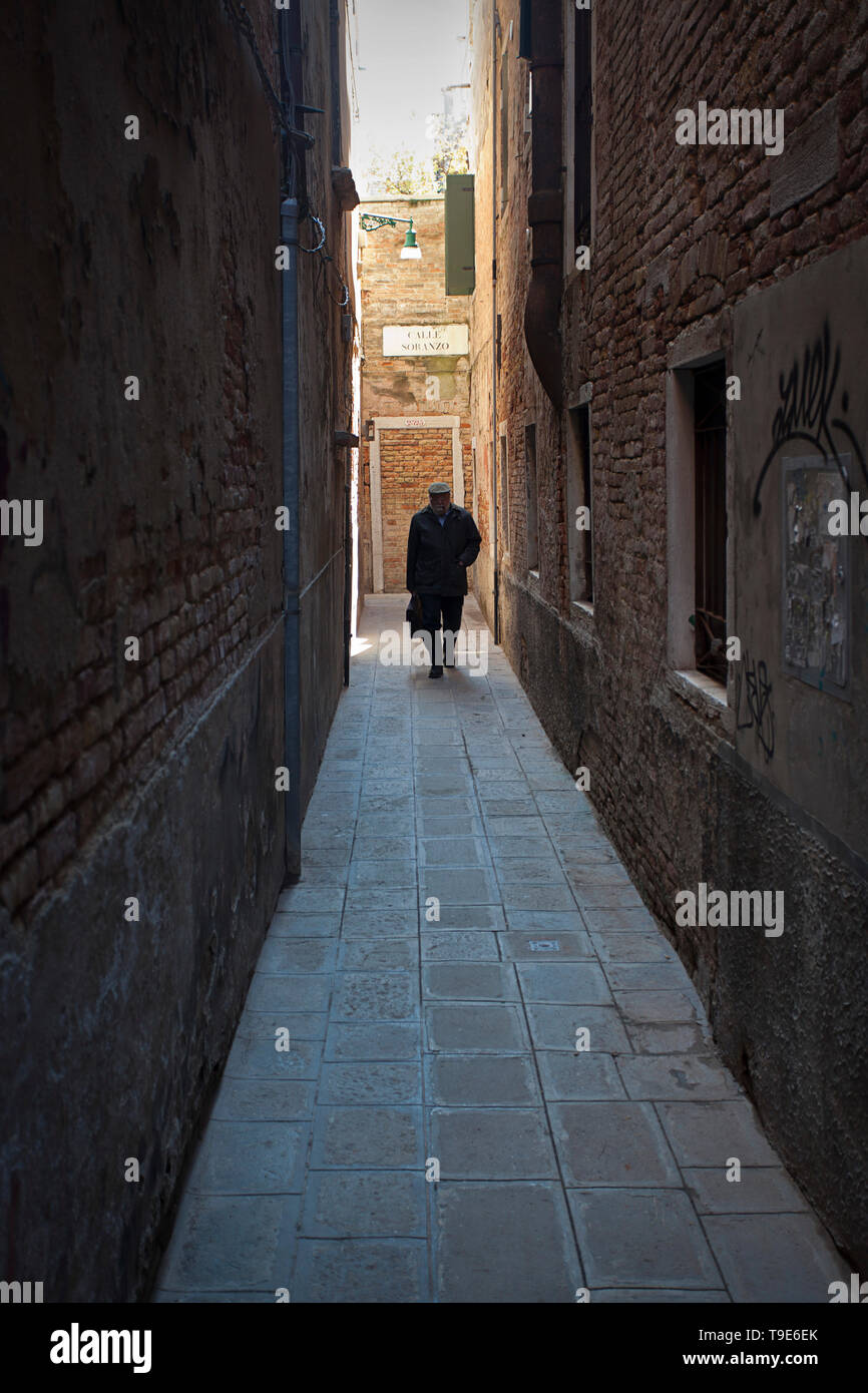 Man walking alone in alley Stock Photo
