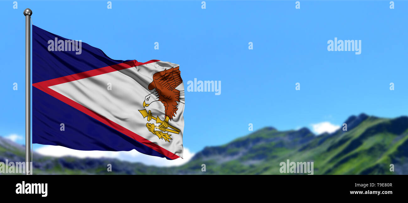American Samoa flag waving in the blue sky with green fields at mountain peak background. Nature theme. Stock Photo