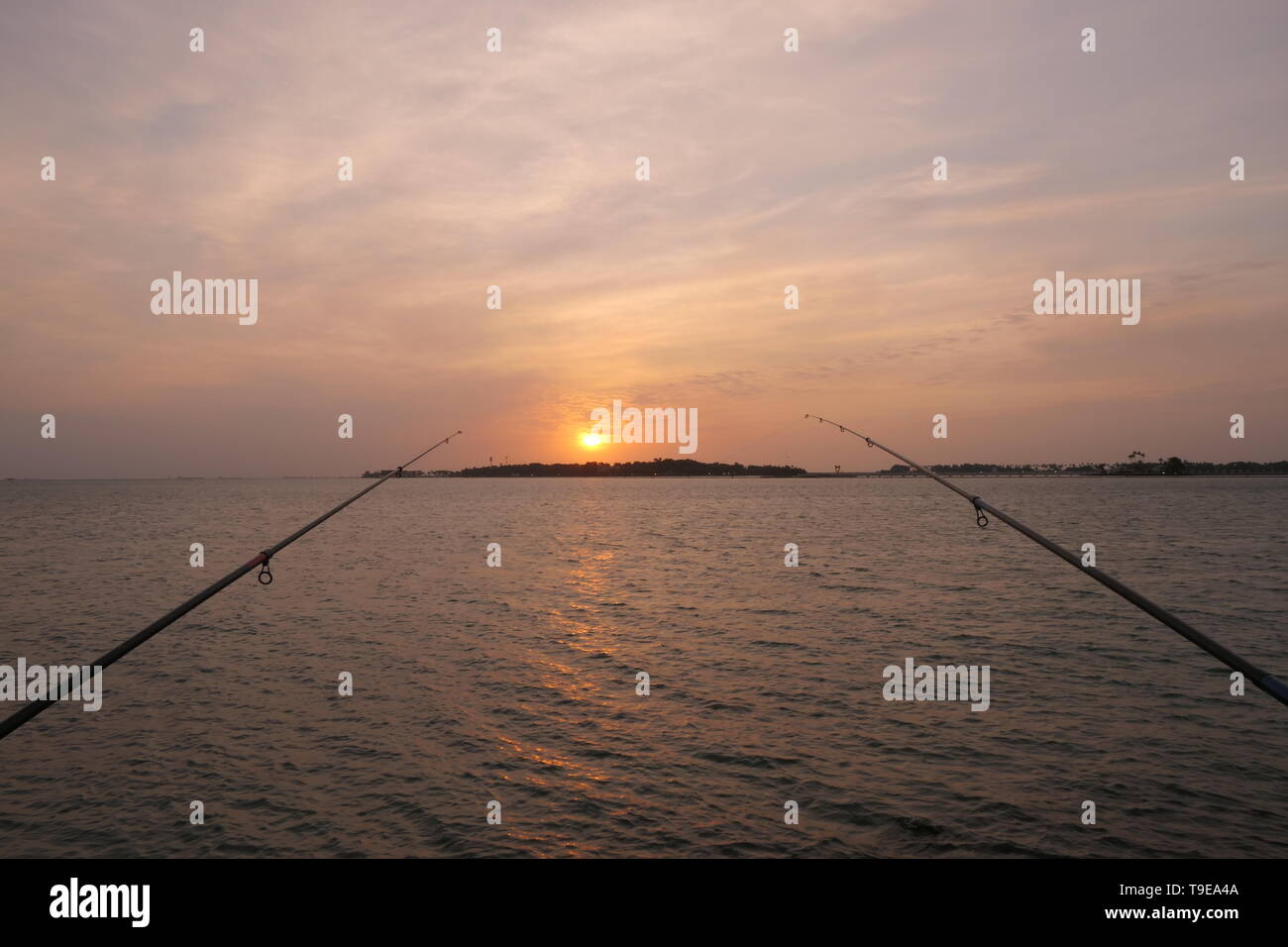 Natural and beautiful sunset with clear clouds and fishing rods in the background, at the coast of Jeddah, Saudi Arabia Stock Photo