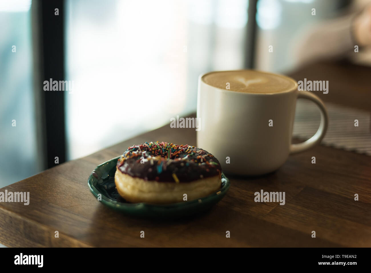coffee with a heart made of milk and a donut on a wooden table. Bad