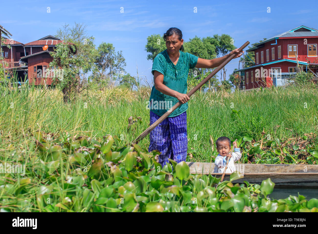 Woman with her child on a canoe in the middle of her floating vegetable garden Stock Photo