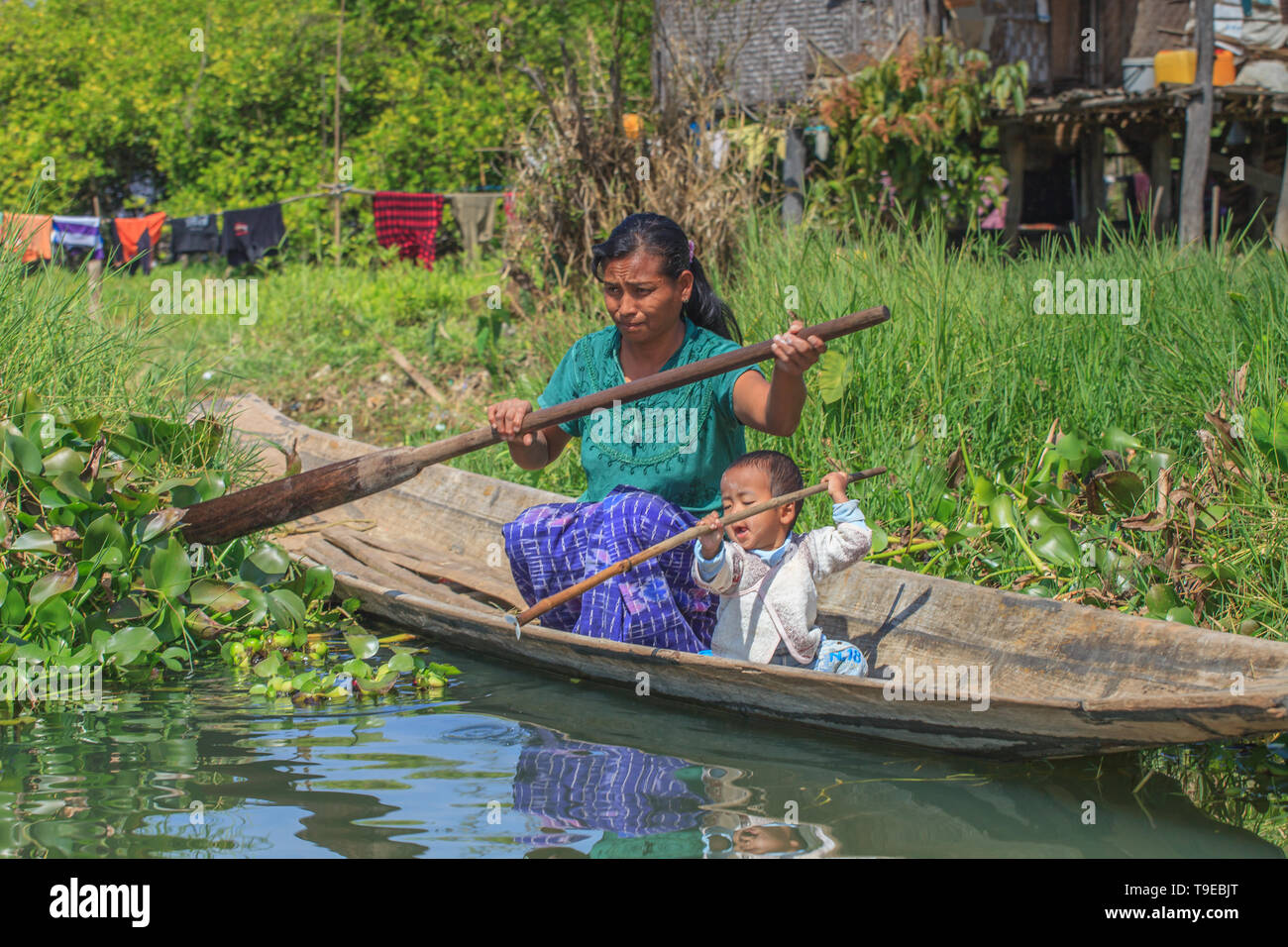 Woman with her child on a canoe in the middle of her floating vegetable garden Stock Photo