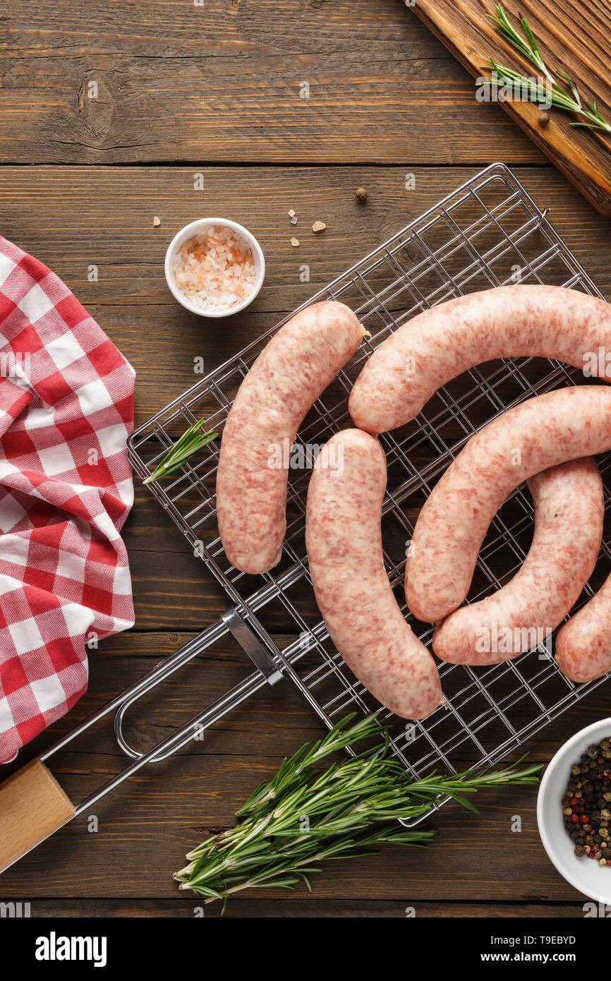 Raw sausages on grill with herbs and spices. Food making or BBQ preparation concept Stock Photo