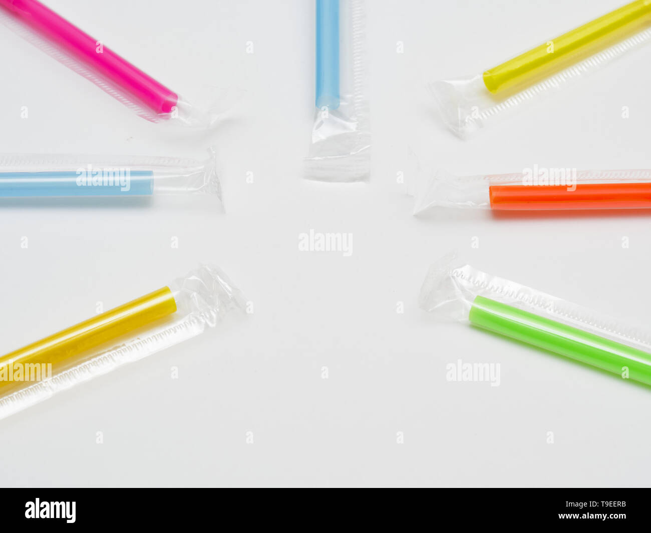 Many multicolored plastic straws forming a circle. Isolated on white background with empty space for caption. Plastic straws are being banned in vario Stock Photo
