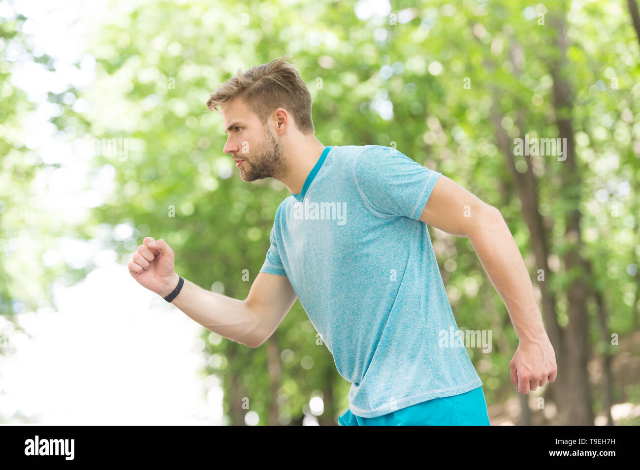 Moving to his goal. Man confident young running in park, side view. Sportsman ambitiously moves to achieve sport goal. Masculinity and sport achieveme Stock Photo