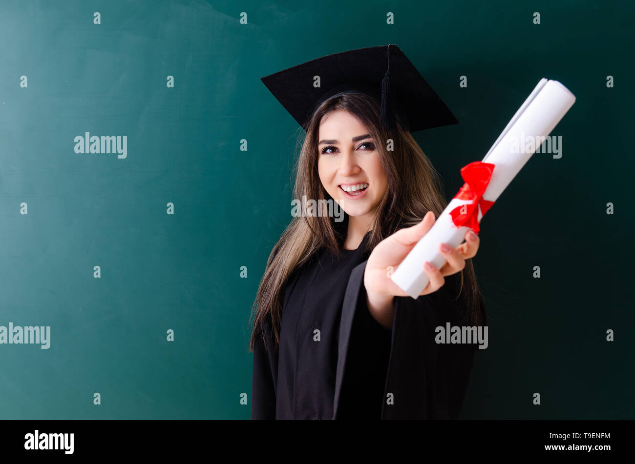 Female graduate student in front of green board Stock Photo - Alamy