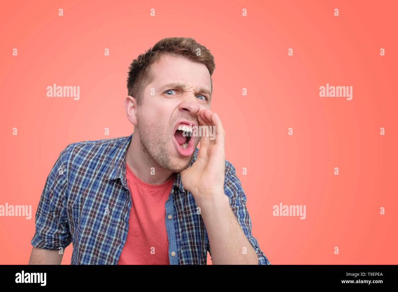 Young european man shouting on colored wall. Stock Photo