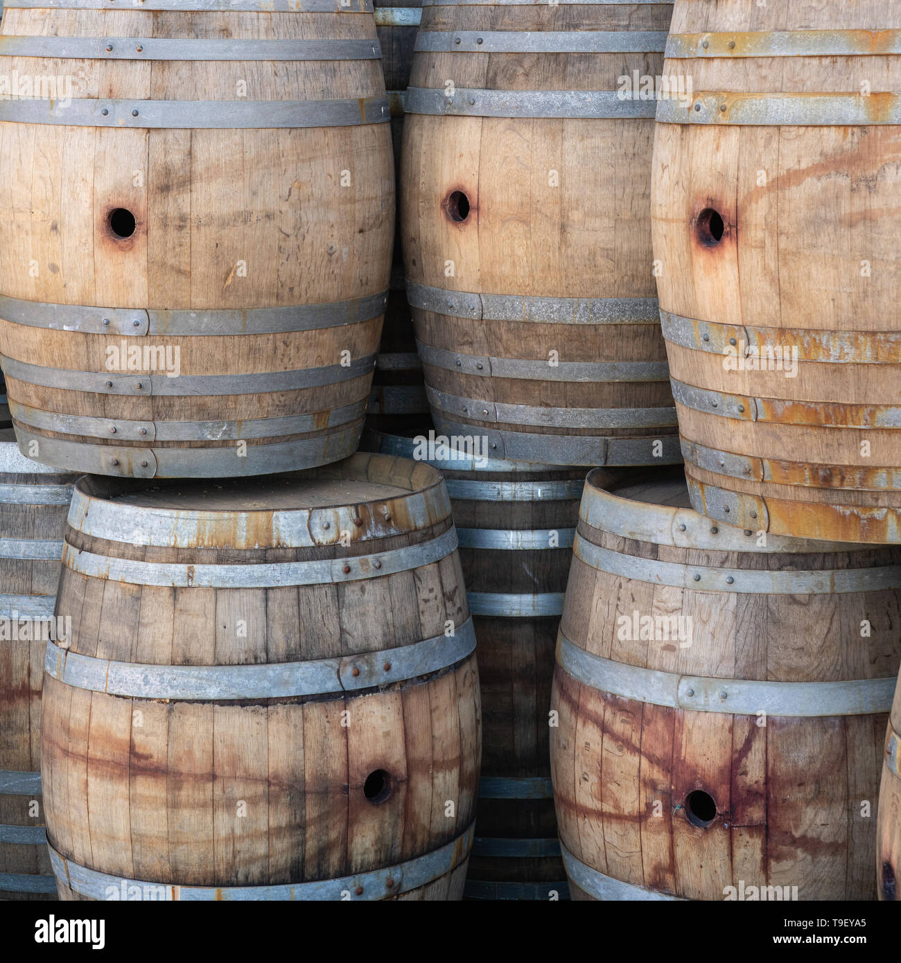 stack of multiple oak barrels used for aging wine with stains from red