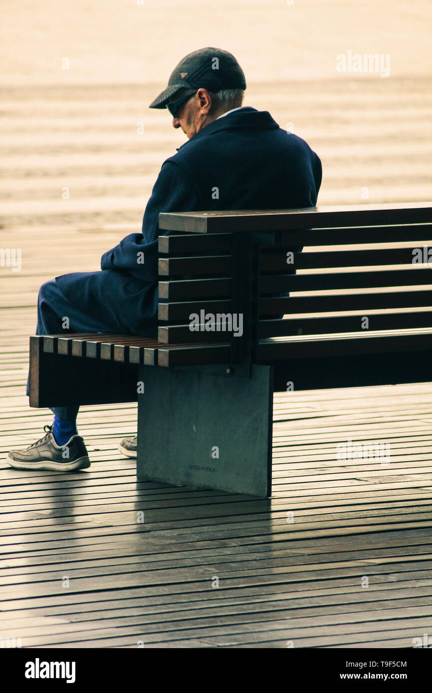 old man sitting alone on a bench in Barcelona, Spain Stock Photo