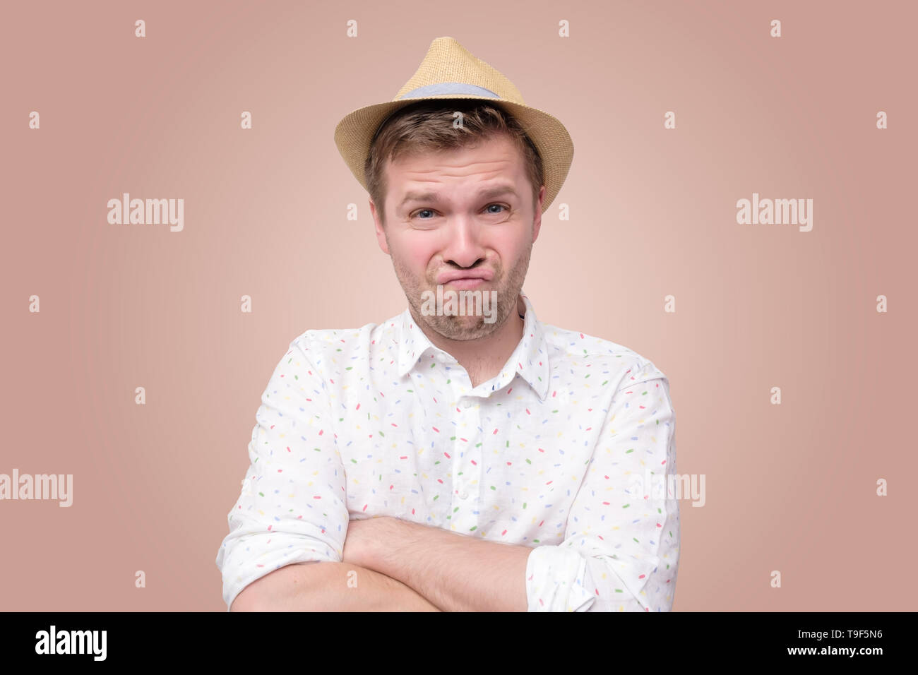Suspicious young man curves lips has hesitations Stock Photo