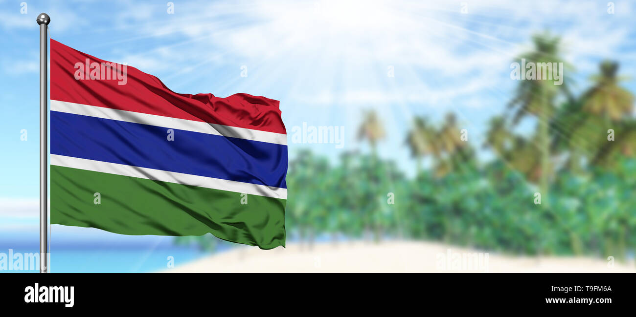 Waving Gambia flag in the sunny blue sky with summer beach background ...