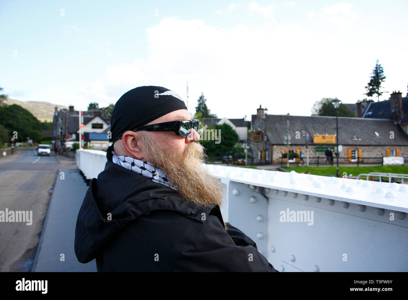 Mann mit langem Bart, Brille und Kopftuch, steht nachdenklich an der Schleuse am Caledonian Canal Stock Photo