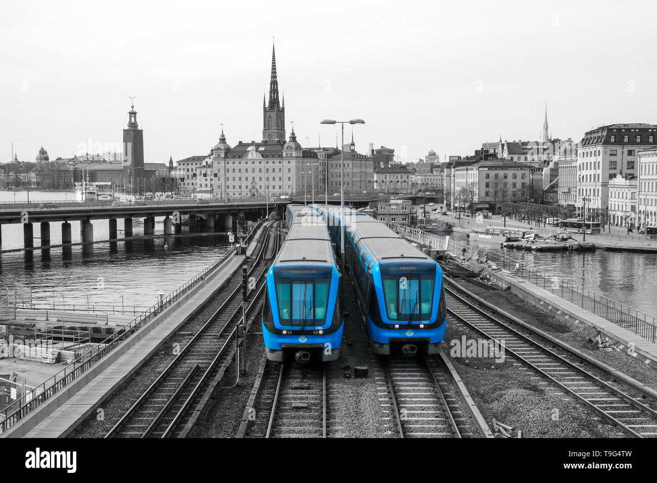 A traditional modern swedish metro train in Stockholm is driving on the bridge from the old town centrum. The train is isolated in a black and white Stock Photo