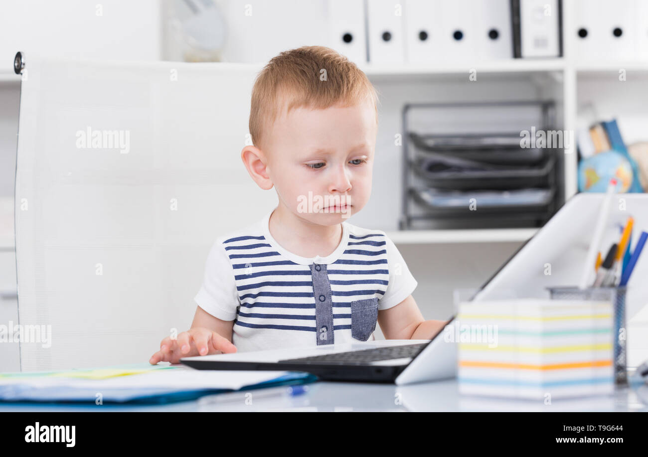 Young boy is watching cartoons on laptop in the office. Stock Photo