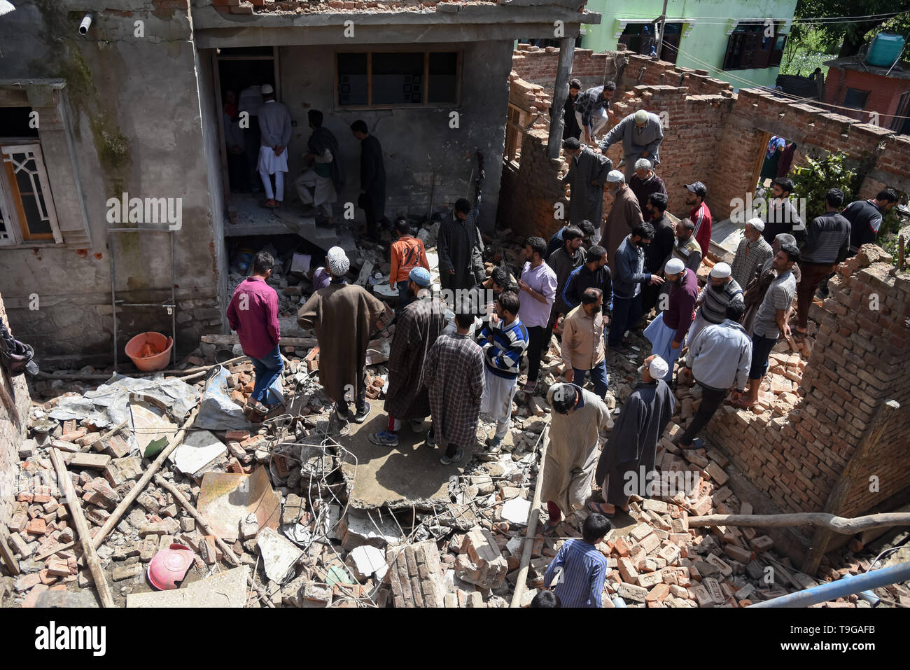 Kashmiri villagers are seen gathered around a partially damaged house after a gunfight in Pulwama, South of Srinagar. Four Kashmiri Rebels were killed on Saturday in two separate gunfights in Jammu and Kashmir’s Pulwama and Baramulla districts. Stock Photo