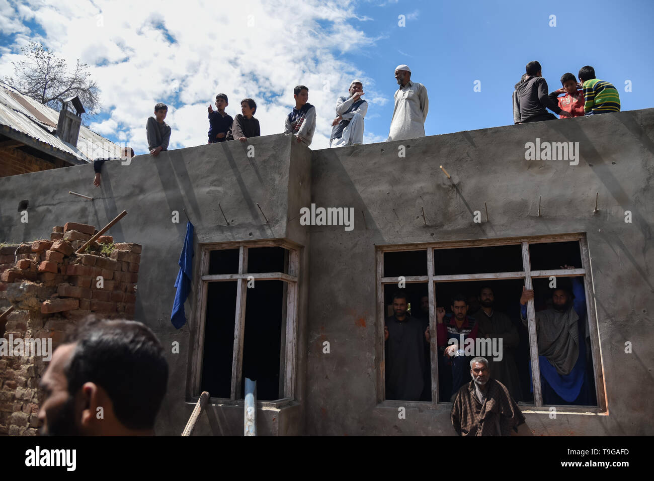 Kashmiri villagers are seen gathered around a partially damaged house after a gunfight in Pulwama, South of Srinagar. Four Kashmiri Rebels were killed on Saturday in two separate gunfights in Jammu and Kashmir’s Pulwama and Baramulla districts. Stock Photo