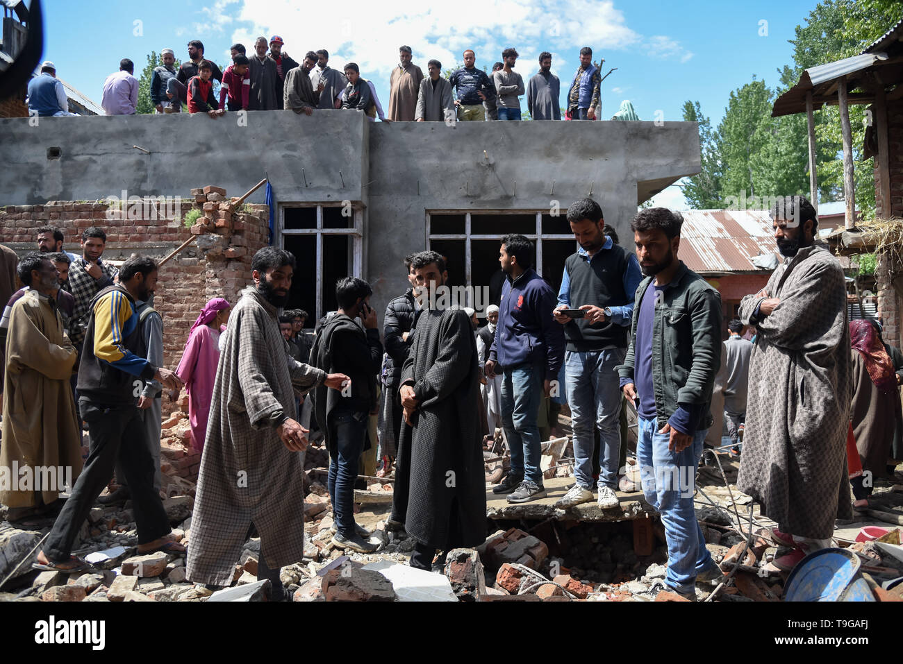 Kashmiri villagers are seen gathered around a partially damaged house after a gunfight in Pulwama, South of Srinagar. Four Kashmiri Rebels were killed on Saturday in two separate gunfights in Jammu and Kashmir’s Pulwama and Baramulla districts. Stock Photo
