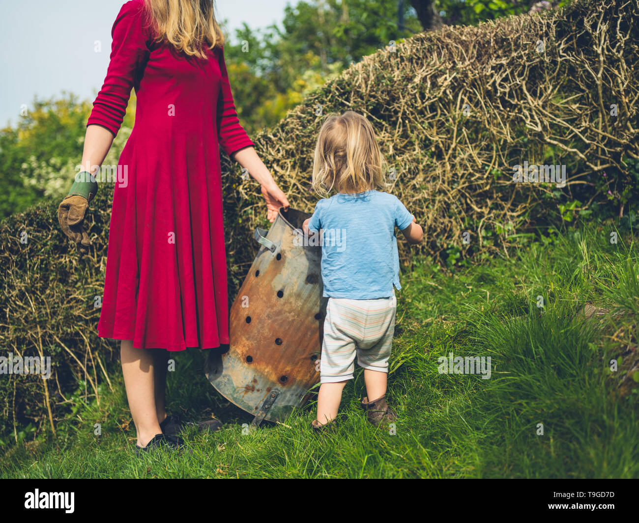 A little toddler is helping his mother weed the garden Stock Photo - Alamy