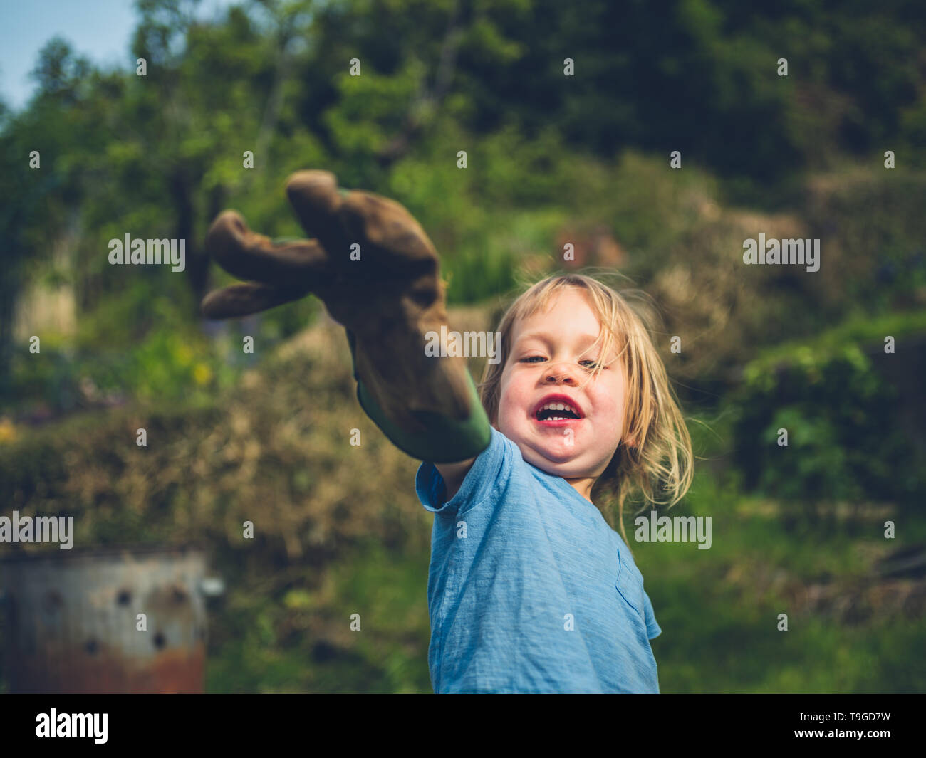 A little toddler is posing with a garden glove Stock Photo