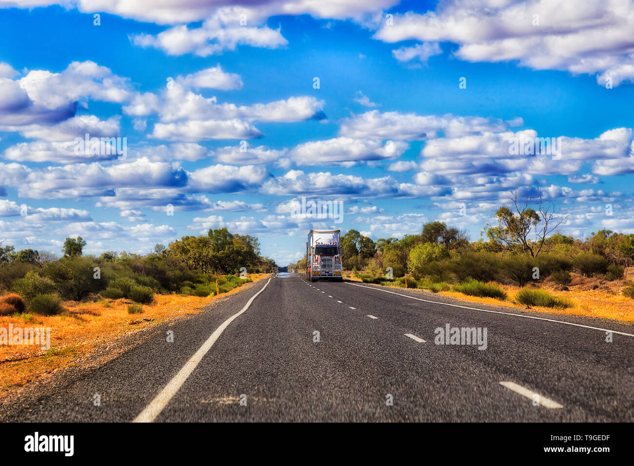 Remote empty road Castlereagh highway B55 in rural outback part of NSW, Australia with lonely distant road train truck transporting cargo shipment. Stock Photo