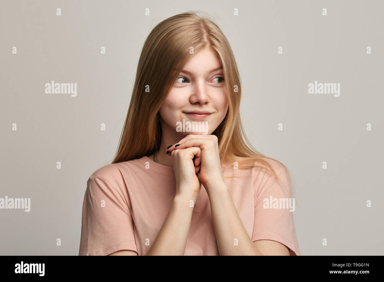 sly-beautiful-girl-planning-evil-trick-holding-hands-in-front-of-her-chest-and-smiling-mysteriously-pensive-cunning-young-woman-with-fists-in-front-of-her-looking-aside-T9GG1N.jpg