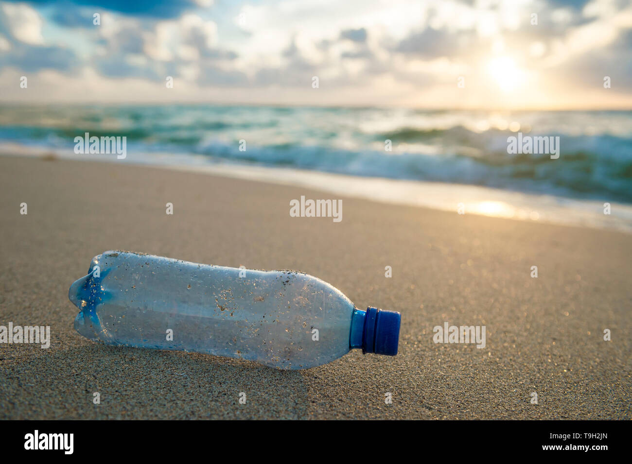 Used plastic water bottle washed up on the shore of a tropical beach, highlighting the worldwide crisis of plastic pollution on even remote islands Stock Photo