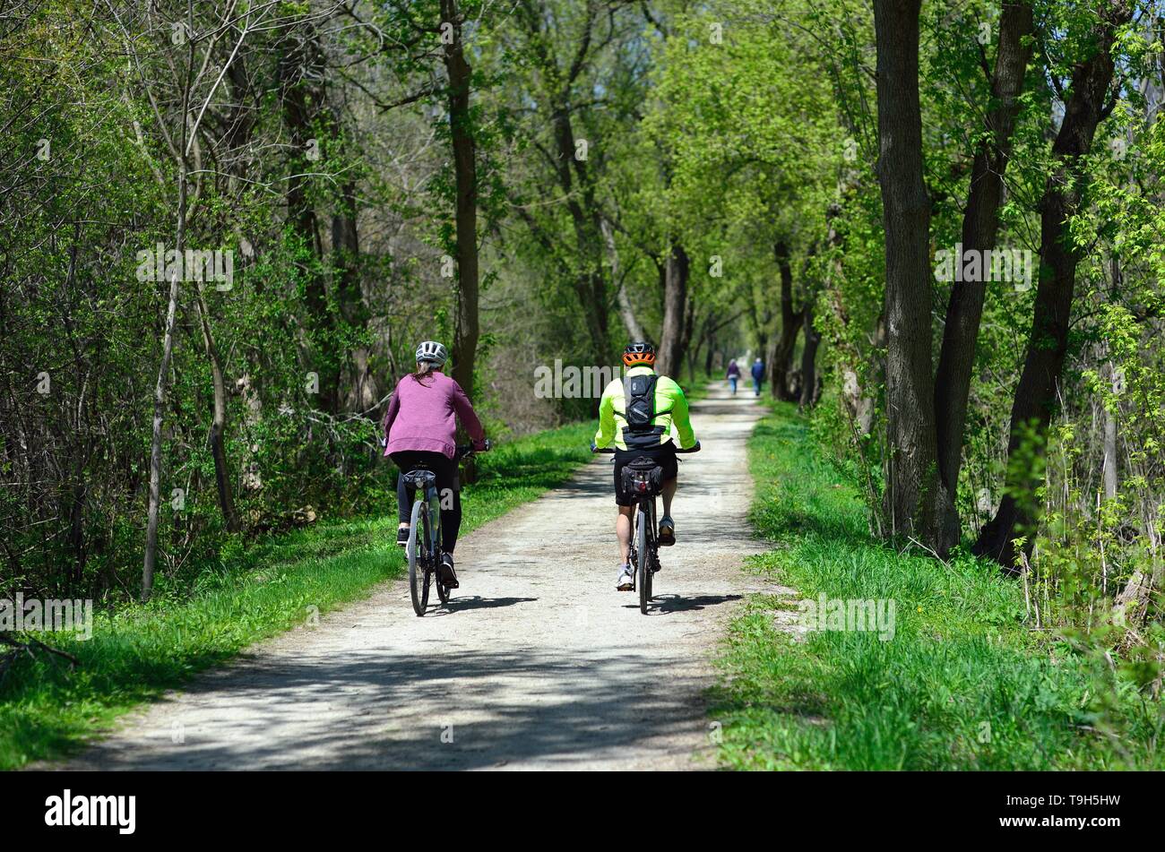 Wayne, Illinois, USA. Couple enjoying a bike ride on a rural path within a forest preserve. Stock Photo